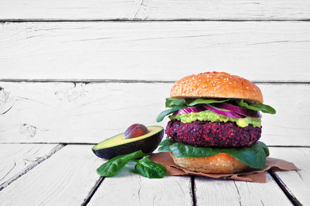 Healthy plant based beet burger with avocado and spinach against a white wood backgroundの写真素材