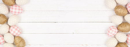 Easter Egg double border of rustic cloth eggs. Top down view over a white wood banner background....