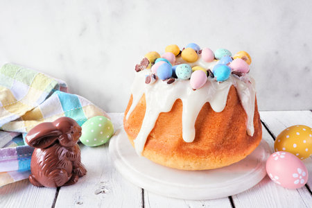 Easter bundt cake decorated colorful chocolate candy eggs. Side view table scene with a bright...