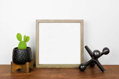 Mock up square wood frame with cactus plant and tabletop decor. Wood shelf against a white wall. Copy space.の写真素材