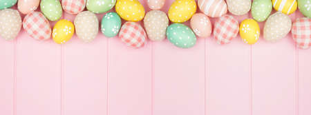 Easter top border with rustic cloth and pastel colored eggs over a pink wood banner background. Overhead view with copy space.の写真素材