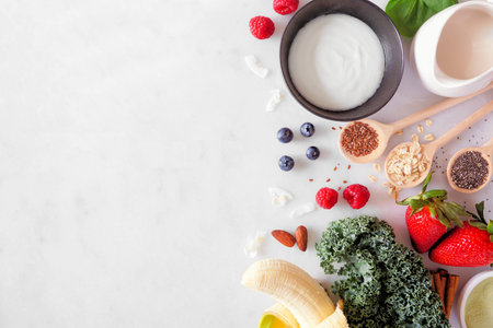 Healthy food side border. Smoothie making concept. Overhead view on a white marble background. Copy...