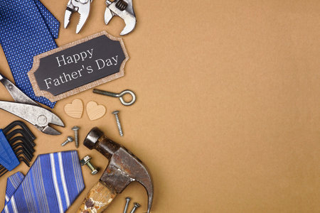 Happy Fathers Day gift tag with side border of ties and tools on a brown paper background. Overhead...