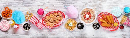 Carnival theme food table scene over a white wood banner background. Overhead view. Summer fair...