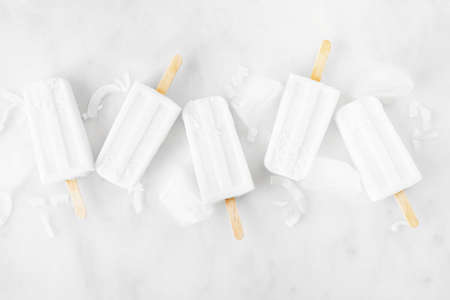 Coconut ice pops scattered over a white marble backgroundの写真素材