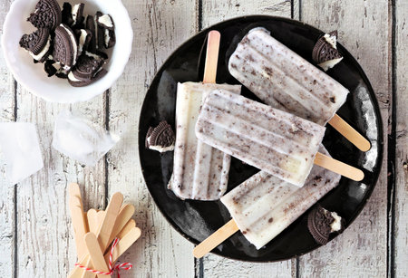 Cookies and cream on a black plate. Top view over a white wood background.