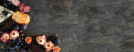 Halloween theme charcuterie corner border against a dark stone banner background. Assorted cheeses and meat appetizers. Copy space.の写真素材