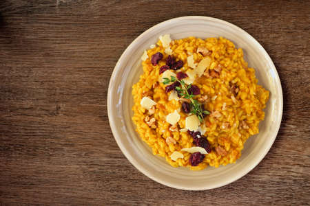 Autumn pumpkin risotto with cranberries and parmesan cheese. Top down view on a rustic wood background.の写真素材