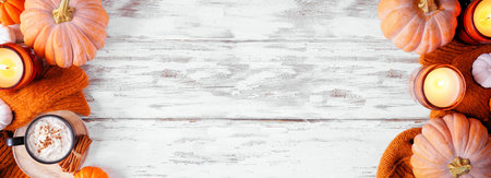 Cozy autumn double border with pumpkins, leaves, sweater and pumpkin spice drink. Above view over a rustic white wood banner background.の写真素材