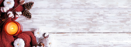 Cozy fall corner border with white pumpkins, sweater, candle and natural decor. Overhead view on a rustic white wood banner background.の写真素材