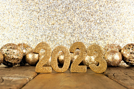 Shiny 2023 numbers with golden baubles and glittery background. New Years Eve concept.