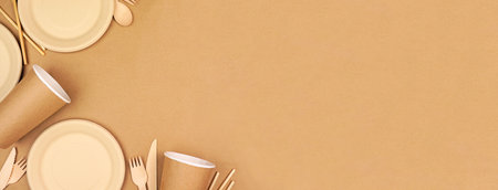 Eco friendly disposable dishware for takeout. Corner border on a brown paper background. Biodegradable, composable alternative to plastic. Top down view with copy space.の写真素材