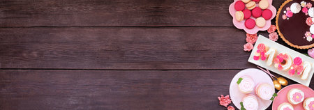 Mothers Day side border with a variety of desserts and sweets. Overhead view on a dark wood banner background. Pink flowers theme. Copy space.の写真素材