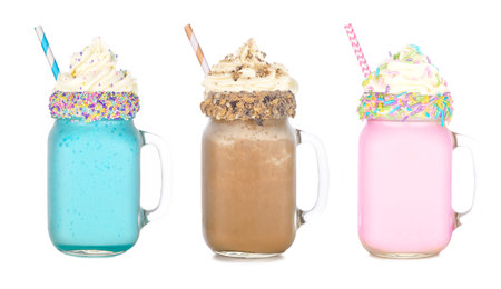 Fun colorful summer milkshakes in mason jar glasses isolated on a white background. Blueberry, chocolate and strawberry sweet drinks.の写真素材