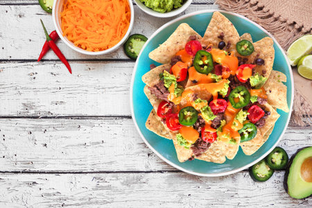 Fully loaded nachos with beef and cheese. Mexican food dish. Top view table scene on a rustic white wood background. Copy space.の写真素材