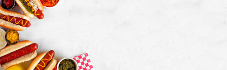 Group of hot dogs with a selection of toppings and condiments. Top view corner border on a white marble background.の写真素材
