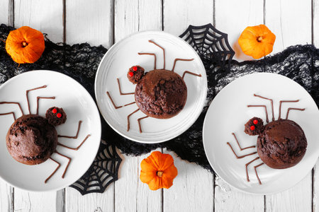 Spooky Halloween spider muffins. Above view table scene over a white wood background.の写真素材