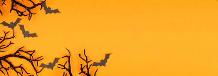 Halloween corner border of spooky bats and black branches. Above view over an orange banner...