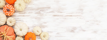 Autumn farmhouse pumpkin corner border over a white wood banner background. Rustic orange and white cloth pumpkins. Top down view with copy space.の写真素材