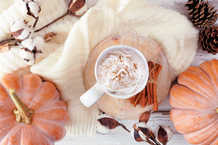 Cozy autumn table scene with pumpkins, sweater, natural decor and pumpkin spice latte. Top down view over a white wood background.の写真素材