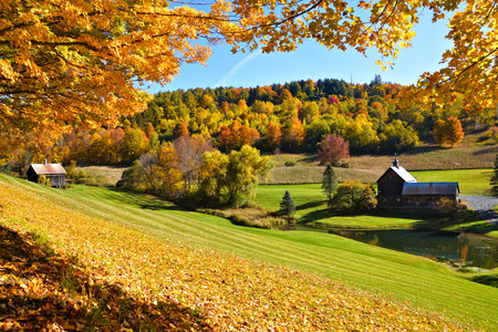 Autumn countryside with frame of colorful leaves and rustic wooden barns near Woodstock, Vermont, USAの写真素材