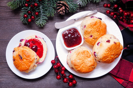 Fresh Cranberry scones with jam. Overhead view table scene on a dark wood background. Christmas theme.の写真素材