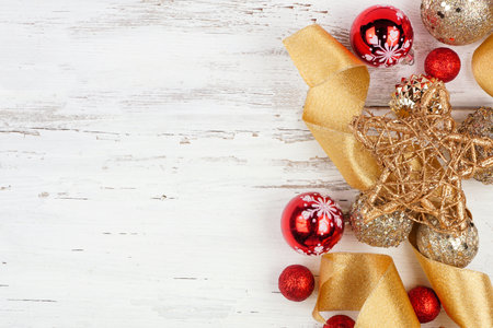 Christmas side border of gold and red ribbon and ornaments. Top view on a white wood background. Copy space.の写真素材