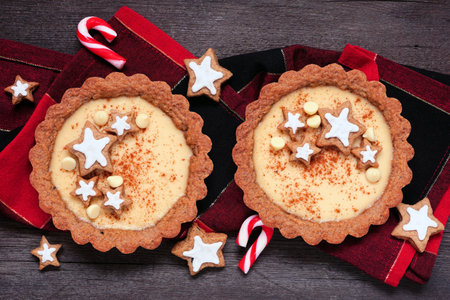 Christmas eggnog and gingerbread tarts. Top view table scene against a dark wood background. Holiday baking concept.の写真素材
