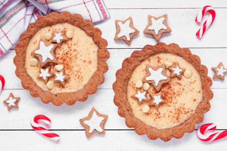 Christmas eggnog and gingerbread tarts. Overhead view table scene against a white wood background. Holiday baking concept.の写真素材