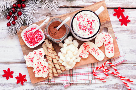 Christmas hot chocolate tray a variety of sweet toppings. Above view table scene on a white wood background.の写真素材