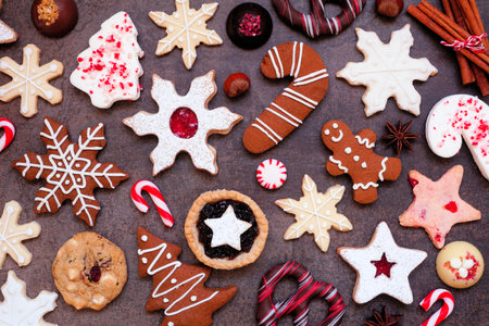 Christmas baking background with assorted cookies and sweet treats. Overhead view on a dark stone background. Holiday baking concept.の写真素材