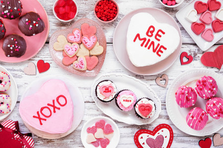 Valentines Day table scene with assorted fun desserts and sweets. Overhead view on a white wood background. Love and hearts theme.の写真素材