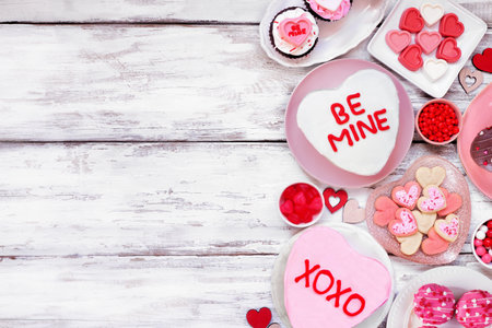 Valentines Day side border with a selection of fun desserts and sweets. Top down view on a white wood background. Love and hearts theme. Copy space.の写真素材
