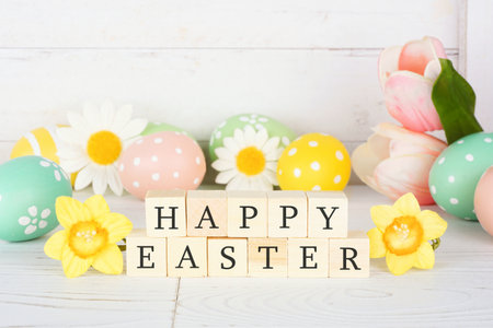 Happy Easter wooden blocks with flowers and eggs against a white wood backgroundの写真素材