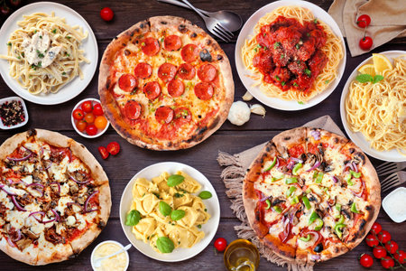 Delicious Italian food table scene. Assortment of pizzas and pastas. Top view on a dark wood background.の写真素材