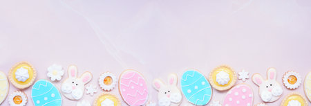 Easter or spring themed baking bottom border with assorted cookies and sweet desserts. Top down view on a pink stone banner background with copy space.の写真素材