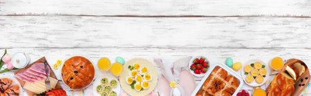 Easter breakfast or brunch bottom border. Top view on a white wood banner background. Breads, quiche and an assortment of spring food items. Copy space.の写真素材