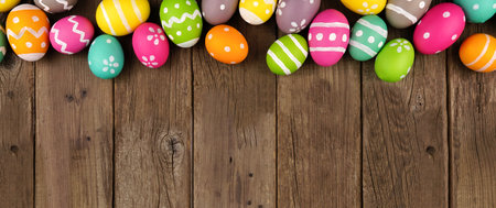 Colorful Easter Egg top border  against a rustic old wood banner background. Above view with copy space.の写真素材