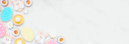 Easter or spring themed baking corner border with assorted cookies and sweet desserts. Above view on a white marble banner background with copy space.の写真素材