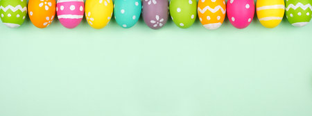 Colorful Easter Egg top border over a soft green paper banner background. Copy space.の写真素材