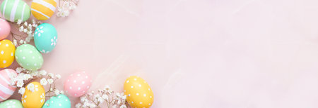Pastel Easter eggs and white spring flowers. Top down view corner border against a soft pink stone banner background. Copy space.の写真素材
