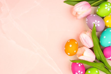Colorful Easter eggs and pink spring tulip flowers. Top view bottom border against a pink stone banner background. Copy space.の写真素材