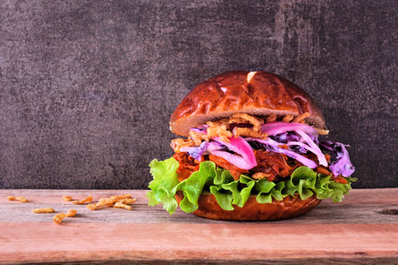 Vegan jackfruit burger against a dark wood background. Healthy eating, plant-based pulled pork meat substitute concept.の写真素材