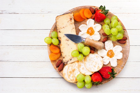 Summer theme charcuterie board against a white wood background. Variety of fruits, cheeses and crackers. Overhead view.の写真素材