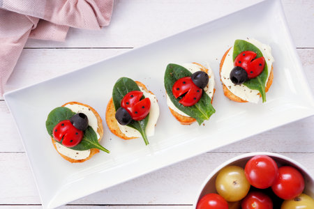 Fun summer theme ladybug crostini appetizers. Top view table scene against a dark background. Above view.の写真素材