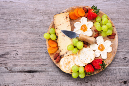 Summer theme charcuterie board against a wood background. Selection of fruits, cheeses and crackers. Top view.の写真素材