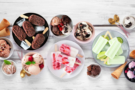 Cool summer food table scene. Variety of ice cream bowls, popsicles and frozen treats. Above view on a white wood background.の写真素材