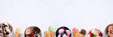 Summer ice cream bottom border. Bowls and cones of colorful assorted flavors. Top view on a white marble banner background. Copy space.の写真素材