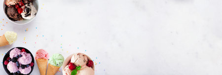 Summer ice cream corner border. Bowls and cones of colorful assorted flavors. Top view on a white marble banner background. Copy space.の写真素材