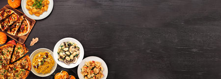 Delicious autumn meal corner border. Top down view on a black wood banner background. Pumpkin and...